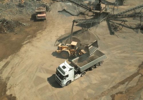 The process of loading coal into a truck. Yellow digger machine with metal shovel.